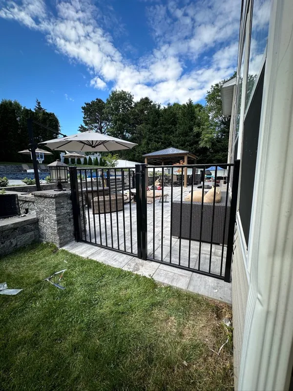 Paver pool deck with stone seat wall and safety gate by Alec's Construction