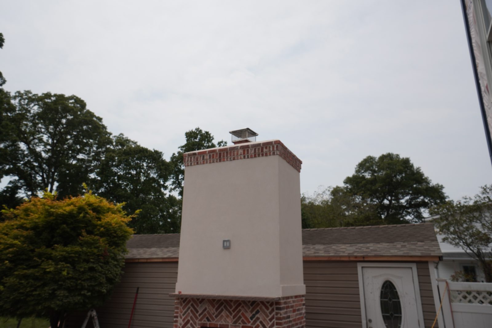 Custom stucco chimney with brick crown detail against the sky