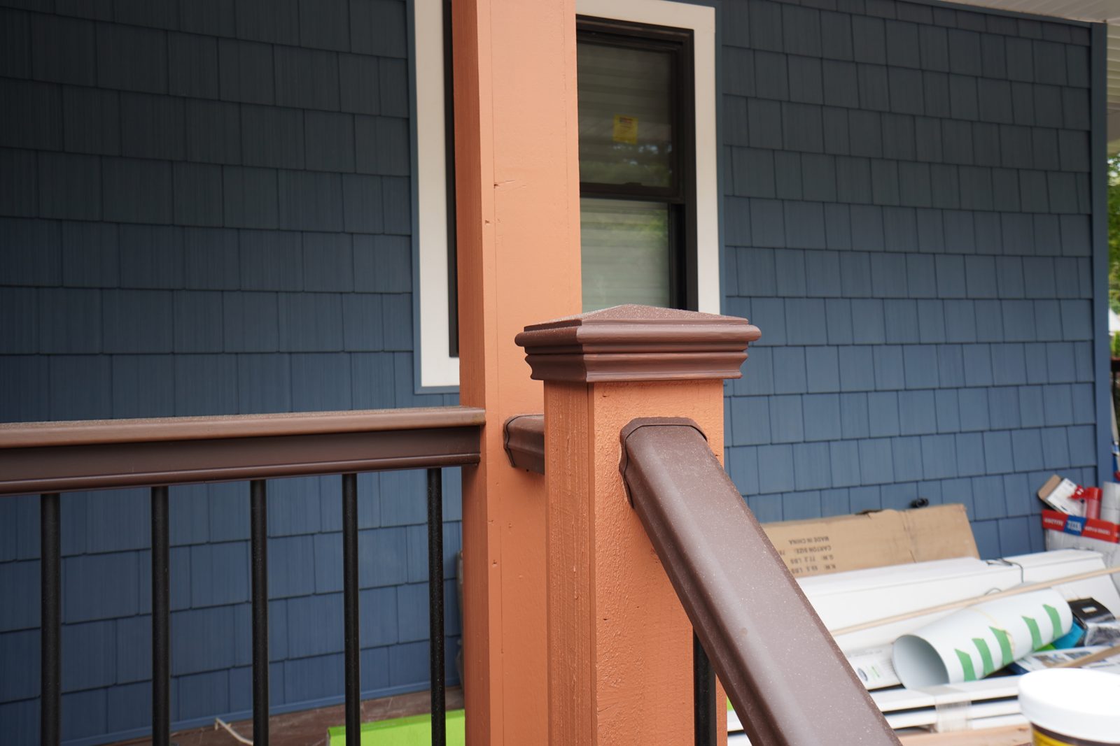 Custom porch railing post with cap moulding and black aluminum balusters