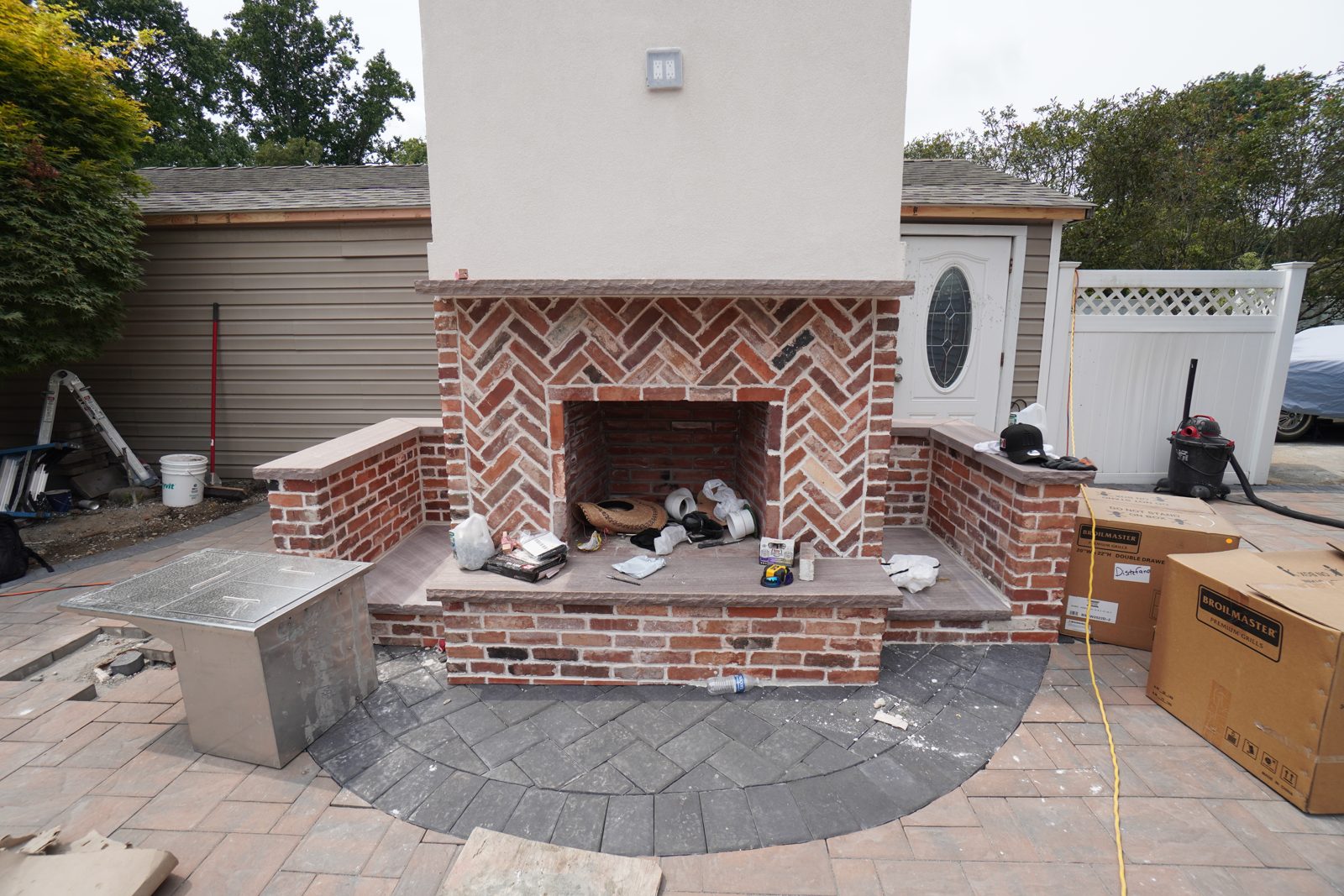 Outdoor brick fireplace with herringbone firebox and stucco chimney