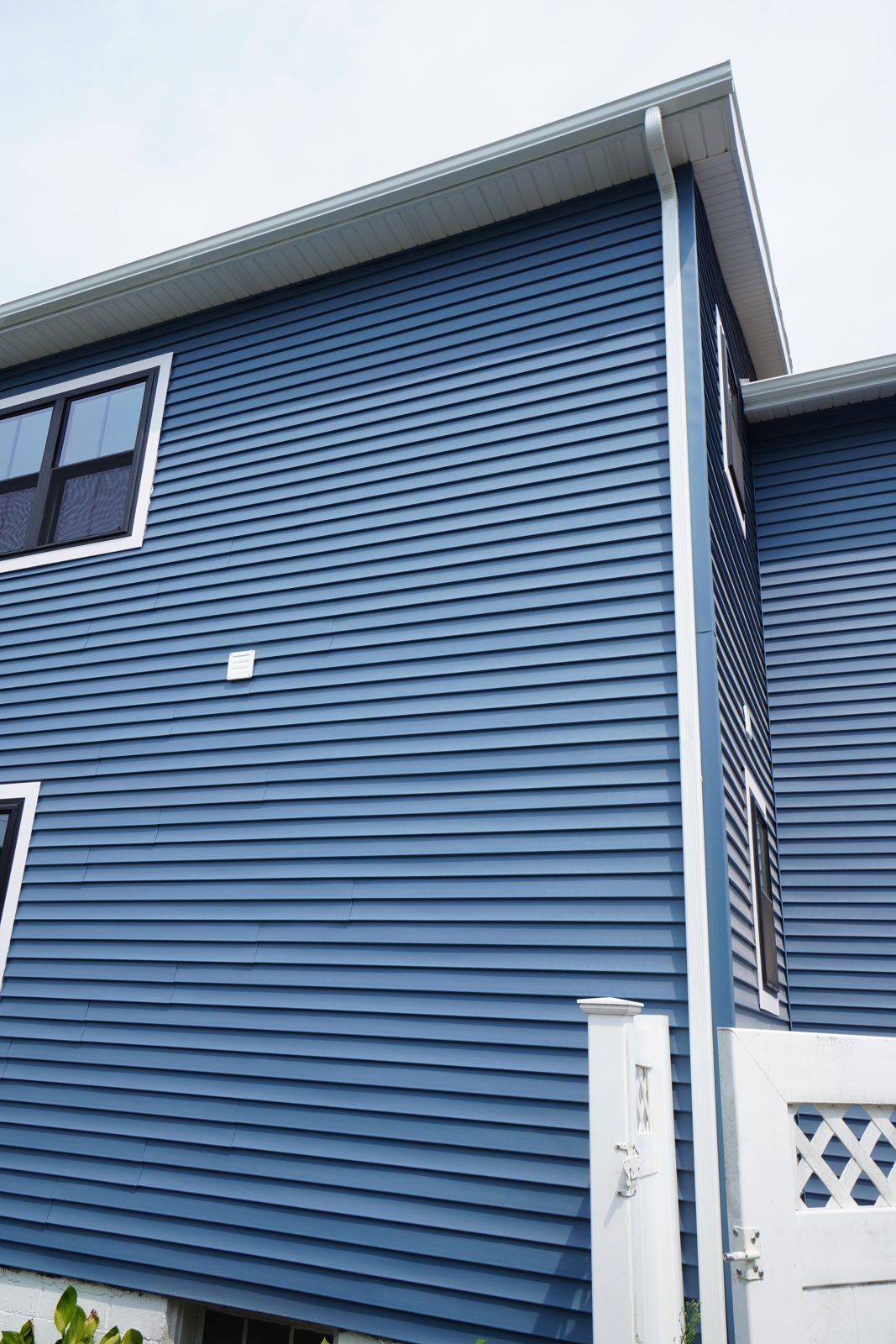 Vinyl siding corner detail with white window frames and trim