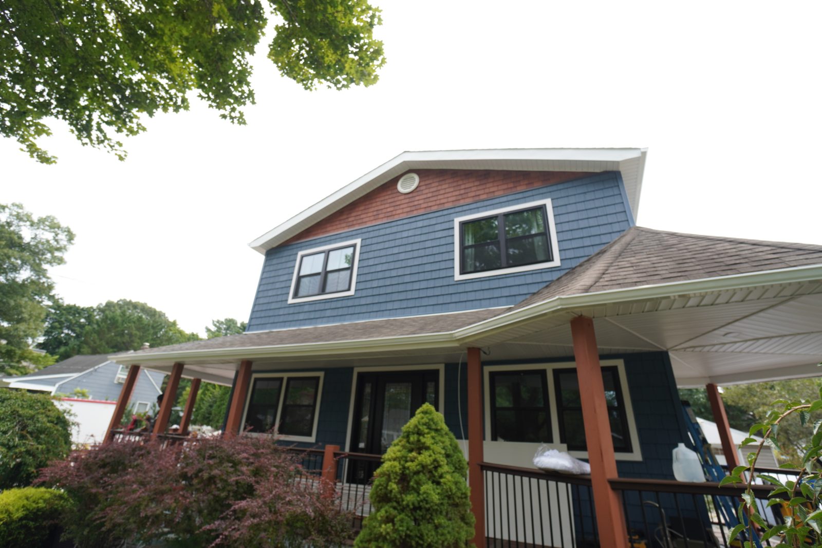 Wraparound porch with custom columns, black railings, and crown moulding