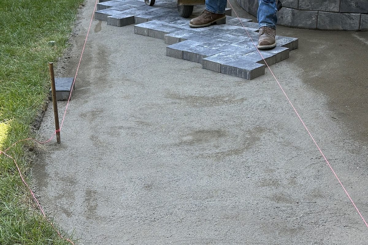 Screeded bedding sand base with pavers being laid by Alec's Construction