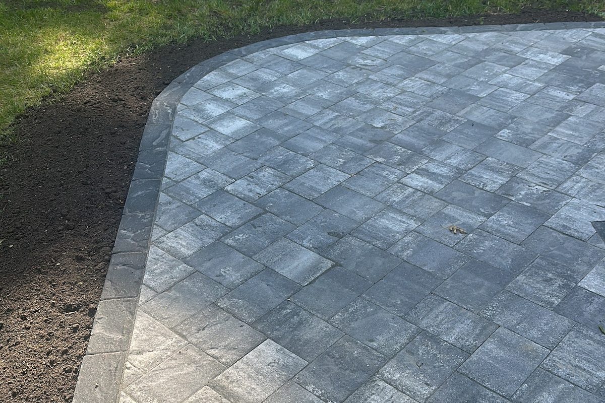 Paver patio with a curved soldier-course border by Alec's Construction