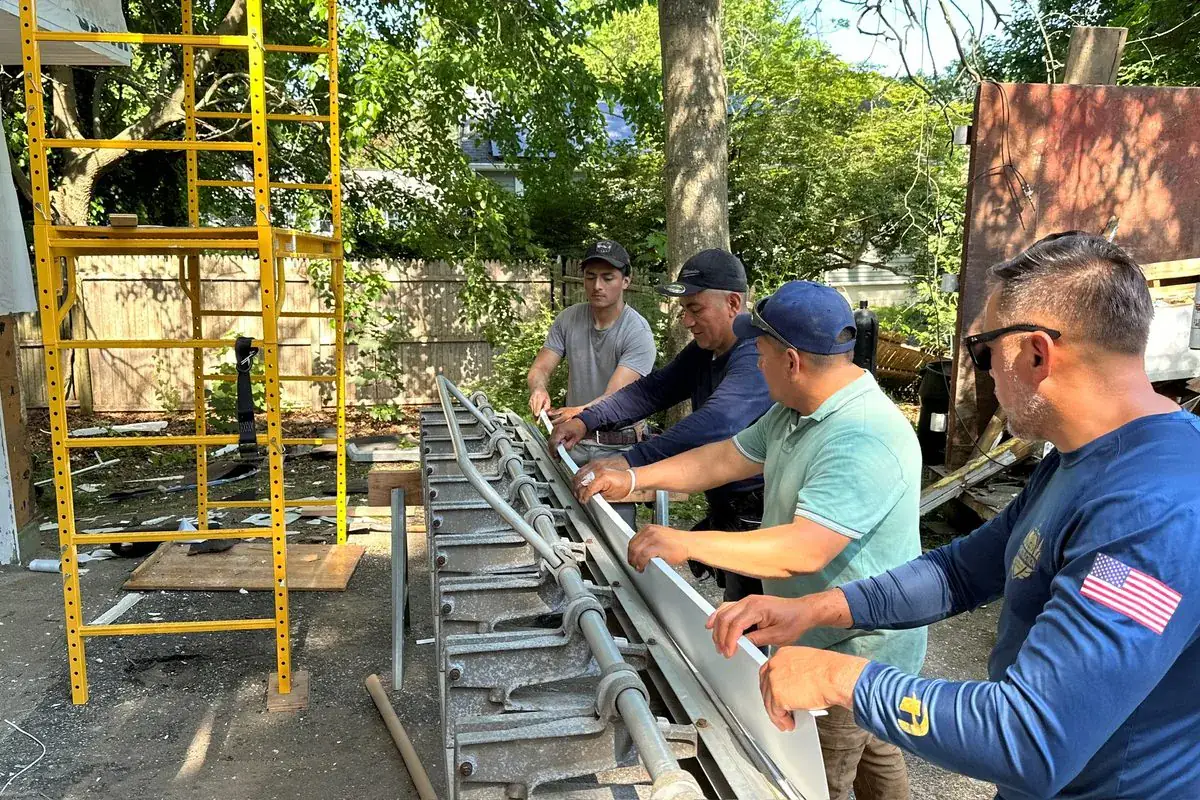Alec's Construction crew bending trim stock on a metal brake during a siding job